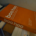 An orange copy of Boo Hoo resting on other books.